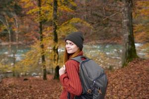 otoño bosque naturaleza paisaje alto arboles y mujer caminante con mochila foto