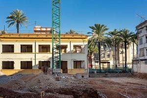 unfinished building at the construction site, in the city on a sunny day, palm trees, construction crane photo