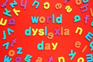 Color alphabet letters on red background. World Dyslexia Day concept. Solving the educational problem of reading. Medical and mental health awareness. Logopedy, psychology, learning lessons photo