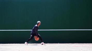 de concept van spelen basketbal en oefening. Aziatisch Mens dribbelen een basketbal video