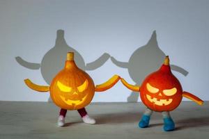 Small orange and red pumpkin with halloween face, legs and hands hold hands. photo