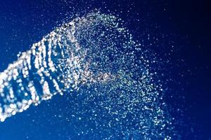 Abstract background. A stream of water with splashes sparkles on a blue background. photo