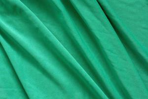 Green fabric texture with beautiful waves. Diagonal waves. Thin soft textile. photo