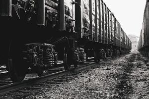 Freight wagons closeup on rails. Stylized black and white photo. A long train, many pairs of wheels with springs. photo