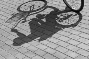 black and white photo of shadow of woman on bicycle