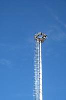 Spotlight tower on the blue sky background, stadium light pole. photo