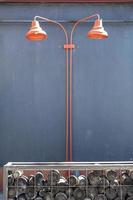 Two red lampshades on a gray wall in the street. Lamp in a wooden box on the background of a gray wall. photo