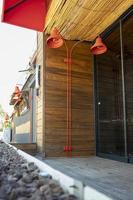 Red lamps on the background of a wooden wall in a cafe. The wooden wall of the building. Coffee shop with red lanterns in the city. Street cafe photo