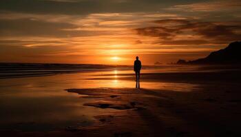 Photo of a sunset silhouette with a person standing on a beach at sunset.