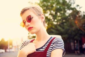 bonito mujer vistiendo Gafas de sol posando al aire libre de cerca foto