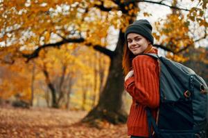 happy woman with backpack walking in park in nature in autumn cropped view photo