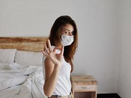 woman on bed medical mask gesturing with hand photo