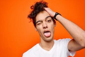 Cheerful guy grimacing white t-shirt close-up orange background photo