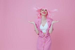 Pretty young female gesturing with hands pink jacket lifestyle glamor pink background unaltered photo