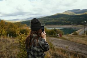 Woman photographs nature in the mountains and a warm hat fresh air in the fall photo