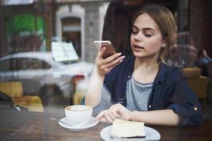 mujer con teléfono en manos chateando desayuno en un café foto