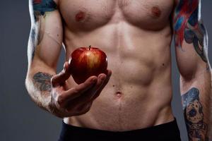 desnudo carrocero con bombeado músculos y tatuaje manzana en mano salud foto
