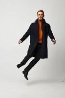 male model jumped up in a black coat in trousers and boots photo