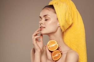 attractive woman with bare shoulders with oranges in hands cropped view beige background photo