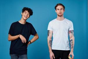 two men in t-shirts on a blue background stand side by side cropped view portrait photo