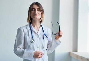 professional doctor woman holding glasses in her hand and stethoscope around her neck photo