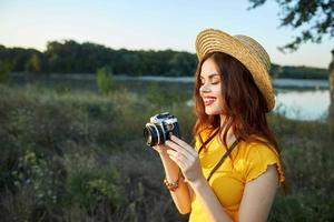 Woman photographer with a camera in her hands smile red lips hat nature landscape photo