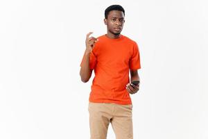 cute African American in a t-shirt and shorts with a mobile phone on a light background photo
