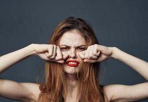 woman with red lips crying on gray background and hands near face cropped view photo