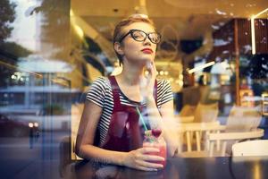 mujer con corto pelo se sienta a un mesa en un café cóctel vacaciones foto