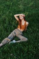 A woman lies on fresh spring green grass in a park without mosquitoes or ticks and enjoys relaxing while watching the sunset. The concept of safe outdoor recreation photo