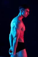 athletic guy with athletic build on a black background side view neon light photo