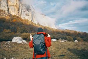 traveler with backpack in autumn in the mountains blue sky clouds high rocks landscape photo