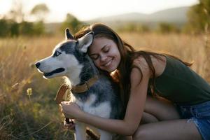 Woman smiling and hugging her dog sitting in a field with a dachshund dog smiling while spending time outdoors with a friend dog in autumn at sunset while traveling photo