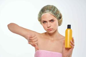 woman in pink towel with cap on her head lotion skin care photo