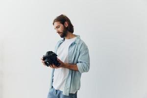 Man hipster photographer in a studio on a white background looking at the camera screen and setting it up for a photo shoot