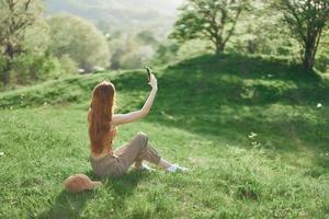 parte superior ver de un mujer con teléfono en mano Lanza libre estudiante molesto a encontrar Internet conexión en naturaleza en un verde verano parque foto