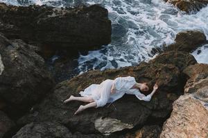 Barefoot woman lying on rocky coast with cracks on rocky surface unaltered photo