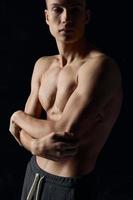 sports guy on a black background naked torso fitness gymnastics arms crossed on his chest photo