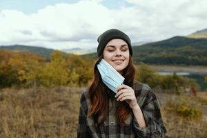 contento mujer en médico máscara en el otoño en el montañas foto