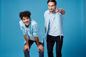 pelo rizado chico en un azul camisa inclinado adelante y un rubio hombre en un azul antecedentes amigos foto