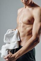 handsome man with towel in hands posing with pumped up body photo