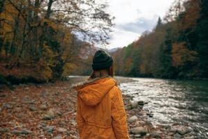 mujer caminando a lo largo el río caído hojas otoño viaje foto