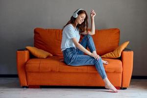 hermosa mujer auricular a hogar en el sofá entretenimiento tecnologías foto