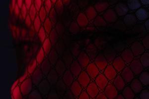 atractivo mujer negro velo en el cara de cerca rojo ligero color antecedentes foto
