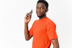 africano americano con móvil teléfono en naranja camiseta nuevo tecnologías foto