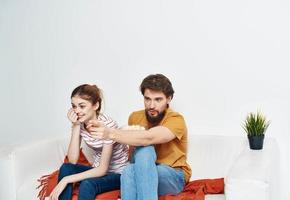 interested man and woman with popcorn on sofa orange plaid and flower in a pot photo