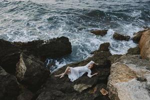 Beautiful bride lying on rocky coast with cracks on rocky surface unaltered photo