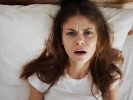upset woman with open mouth lies in bed dissatisfaction close-up photo