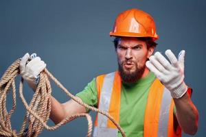 Man in work uniform orange paint rope in hands hard work cropped view photo