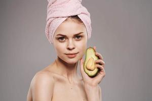 Cheerful woman with a towel on her head cropped view of an avocado in her hand photo